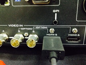 On the Bottom left of the back of the switcher you will find the inputs. Connect your cable, then turn your camera on.
