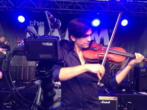 Here the violinist is being filmed at a unique angle, and the black frame and body of the GoPro, paired with the black arm, make it so it blends in with the stage and band equipment. 